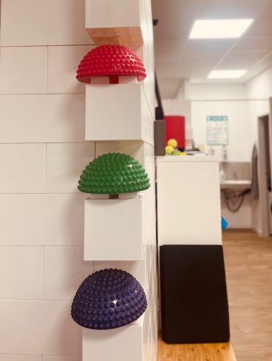 KGG Drei Halbkugeln in Rot, Grün und Lila an einer weißen Wand montiert.