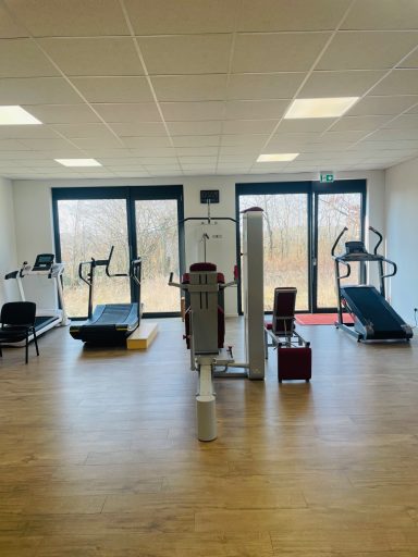 KGG Raum Fitnessraum mit verschiedenen Geräten und großen Fenstern für natürliches Licht.