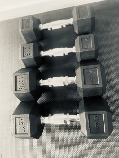 Kurzhantel Schwarze Hanteln in einer Reihe auf einem dunklen Untergrund.